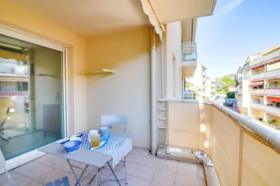 a small table and chair on a balcony with a window at Parc RL Perfect 1 bedroom apartment next to beaches and shops in Cannes
