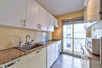 a kitchen with white cabinets and a large window at Appartement le San Francisco bright and calm 3 bedroom flat in Cannes