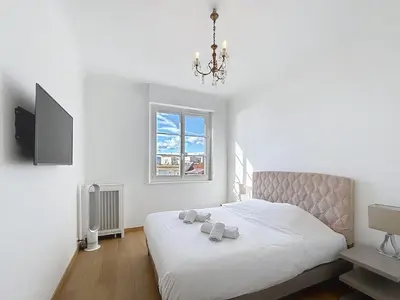 a bedroom with a bed with a chandelier and a window at Palais Alexandre III Magnificent 4 sea view 100m from the Croisette in Cannes