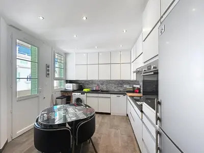 a kitchen with white cabinets and a table in it at Palais Alexandre III Magnificent 4 sea view 100m from the Croisette in Cannes