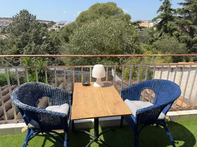 a table with two chairs and a lamp on a balcony at Chambre privée avec salle d’eau et terrasse au calme in Le Cannet
