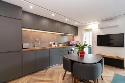 a kitchen with black cabinets and a table and a tv at Heart of Cannes contemporary 2BR garden view Palais & Croisette 5 mn by Olam Properties in Cannes