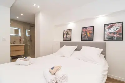 a bedroom with a white bed with towels on it at Heart of Cannes contemporary 2BR garden view Palais & Croisette 5 mn by Olam Properties in Cannes