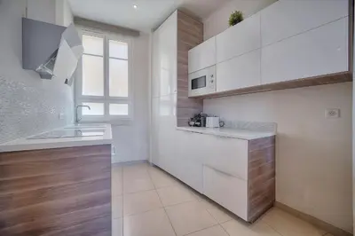 a kitchen with white cabinets and a sink and a window at IMMOGROOM - Palais des festivals within walking distance - balcony - wifi - in Cannes