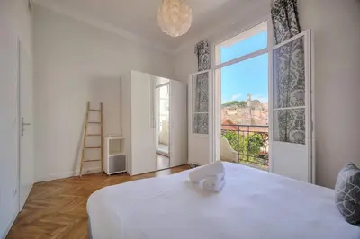 a bedroom with a white bed and a large window at IMMOGROOM - Palais des festivals within walking distance - balcony - wifi - in Cannes
