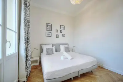 a bedroom with a bed with white sheets and a window at IMMOGROOM - Palais des festivals within walking distance - balcony - wifi - in Cannes