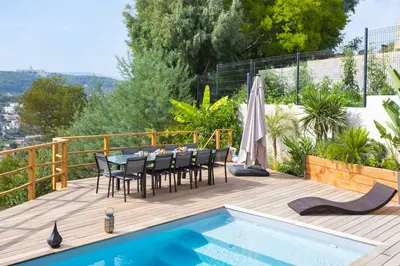 a deck with a table and chairs next to a swimming pool at Villa modern Super-Cannes heated Pool, Parking, CLIM, 7 min to Cannes Beach in Vallauris