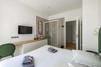 a bedroom with a white bed and a tv on the wall at Superbe appartement 120m2 au coeur de Cannes in Cannes