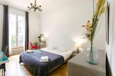 a white bedroom with a bed and a vase of flowers at Cannes Holidays - Charmant, authentique, 3 Chambres, calme, Palais & Plage in Cannes