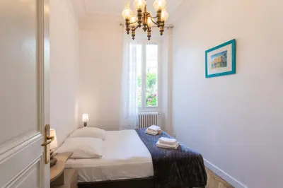 a bedroom with a bed with a chandelier and a window at Cannes Holidays - Charmant, authentique, 3 Chambres, calme, Palais & Plage in Cannes