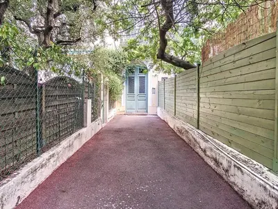 a walkway leading to a blue door in a fence at Quality 1 bedroom rue du Canada 5 mins Croisette 208 in Cannes