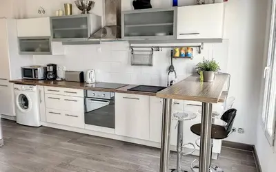 a kitchen with white cabinets and a wooden table at Loft Meynadier by Halldis in Cannes
