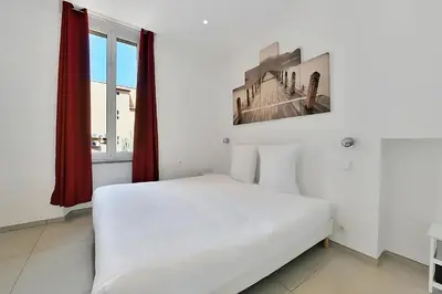a white bed in a room with a window at Nice 2 Rooms in the heart of Cannes in Cannes