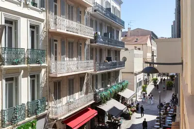 a building with balconies and people walking down a street at Nice 2 Rooms in the heart of Cannes in Cannes