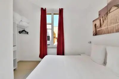 a bedroom with a bed and a window with red curtains at Nice 2 Rooms in the heart of Cannes in Cannes