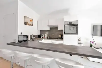 a white kitchen with white appliances and white stools at Nice 2 Rooms in the heart of Cannes in Cannes