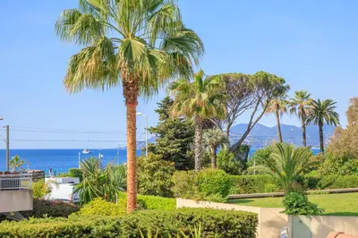 a kitchen and dining room with a white table and chairs at Villa Cynthia - Piscine - Plage (à 50m) - Palais Congrès - Calme absolu in Cannes