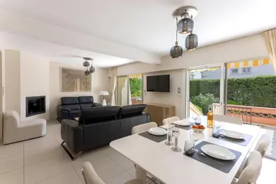 a living room with a dining table and a couch at Villa Cynthia - Piscine - Plage (à 50m) - Palais Congrès - Calme absolu in Cannes
