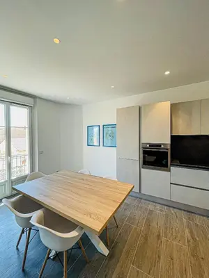 a kitchen with a wooden table and chairs in a room at cote sud deux chambres proche croisette in Cannes