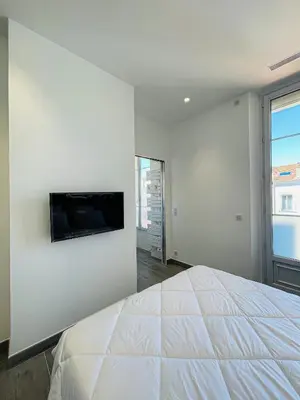 a bedroom with a bed and a flat screen tv on a wall at cote sud deux chambres proche croisette in Cannes