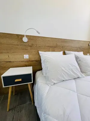 a bed with white pillows and a nightstand with a lamp at cote sud deux chambres proche croisette in Cannes