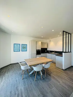 a kitchen and dining room with a wooden table and chairs at cote sud deux chambres proche croisette in Cannes