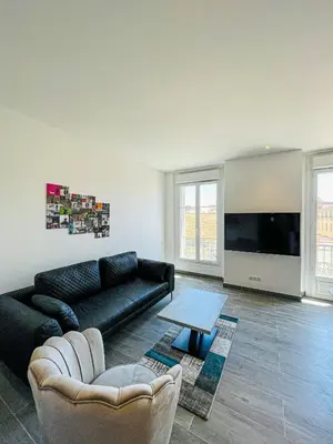 a living room with a black couch and a tv at cote sud deux chambres proche croisette in Cannes