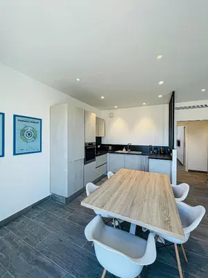 a kitchen with a wooden table and white chairs at cote sud deux chambres proche croisette in Cannes