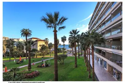 a palm tree in a park next to a building at REF 761 - Cannes Croisette - Sea view apartment for rent in Cannes