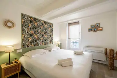 a bedroom with a large white bed with a painting on the wall at Hé Jude le Suquet in Cannes
