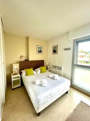 a bedroom with a large white bed with yellow pillows at Appartement Alexandre lumineux avec superbe vue mer in Cannes