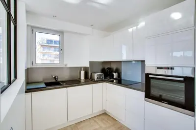 a white kitchen with white cabinets and a window at Appartement Alexandre lumineux avec superbe vue mer in Cannes