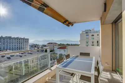 a balcony with a table and a view of a city at Appartement Alexandre lumineux avec superbe vue mer in Cannes