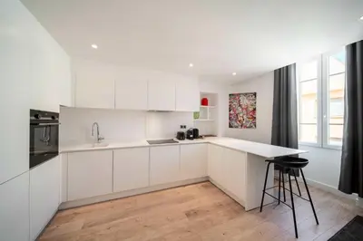 a white kitchen with white cabinets and a counter at Charming apartment for 4 people - Forville Market in Cannes