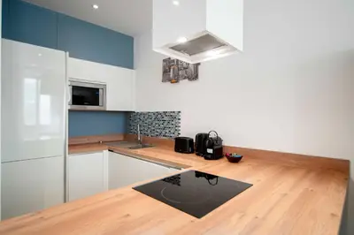 a kitchen with white cabinets and a black rug at Appartement de charme proche Vieux Port et Palais in Cannes