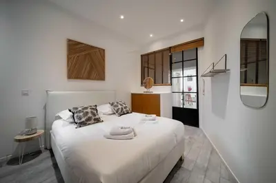 a bedroom with a white bed and a mirror at Appartement de charme proche Vieux Port et Palais in Cannes