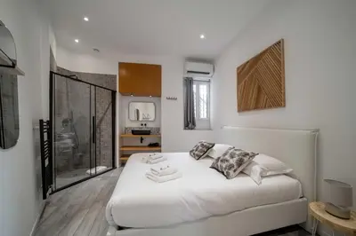 a white bedroom with a large bed and a window at Appartement de charme proche Vieux Port et Palais in Cannes