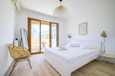 a white bedroom with a bed and a chair at Sublime Two bedroom apartment with Terrace in Cannes