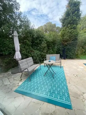 a patio with a table and a chair and an umbrella at Superb Villa, heated swimming pool, central location, secluded gardens in Cannes
