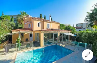 a villa with a swimming pool in front of a house at Superb Villa, heated swimming pool, central location, secluded gardens in Cannes