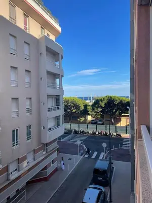 a building with cars parked in a parking lot at Appartement proche mer in Cannes