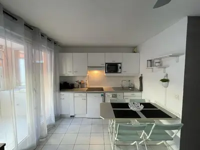 a kitchen with white cabinets and a table and chairs at Appartement proche mer in Cannes