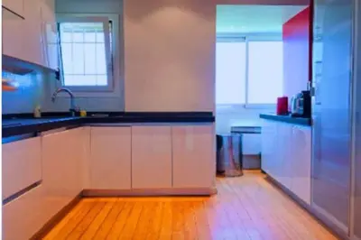 a kitchen with white cabinets and a wooden floor at Penthouse Cannes 100m2 avec 2 suites et terrasse 80m2 in Cannes