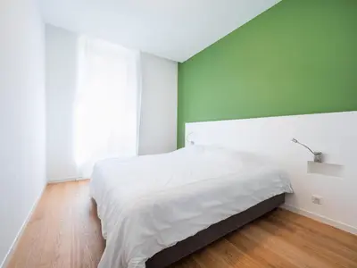 a bedroom with a white bed and a green wall at Appartements proche Croisette, Casino, plages, centre ville et Gare in Cannes