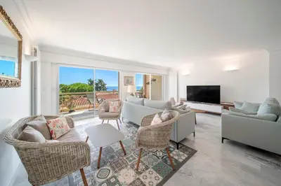 a living room with a couch and chairs and a television at Bright apartment with sea view - Palm Beach in Cannes