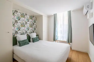 a bedroom with a white bed with a floral headboard at LE MEYNADIER lumineux dans le centre historique, proche des plages et Palais in Cannes