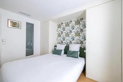 a bedroom with a white bed with two pillows at LE MEYNADIER lumineux dans le centre historique, proche des plages et Palais in Cannes