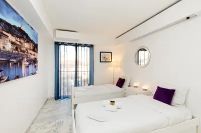 a white room with two beds and a window at Palm Beach 3 chambres in Cannes