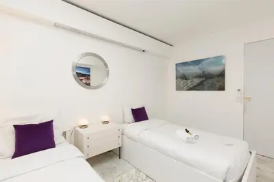 a white room with two beds and a mirror at Palm Beach 3 chambres in Cannes