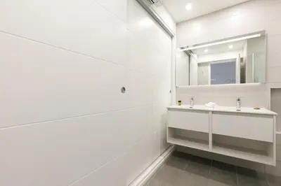 a white bathroom with a sink and a mirror at Palm Beach 3 chambres in Cannes